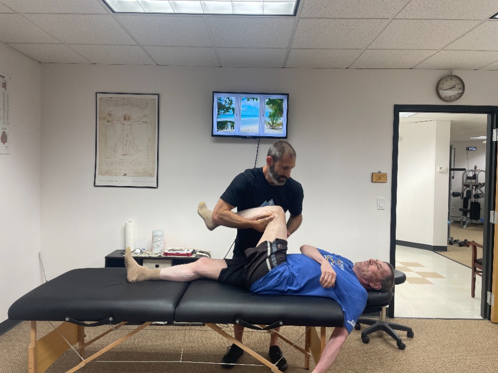 Joshua Lewbel performing a hands on MAT session with a client on the treatment table