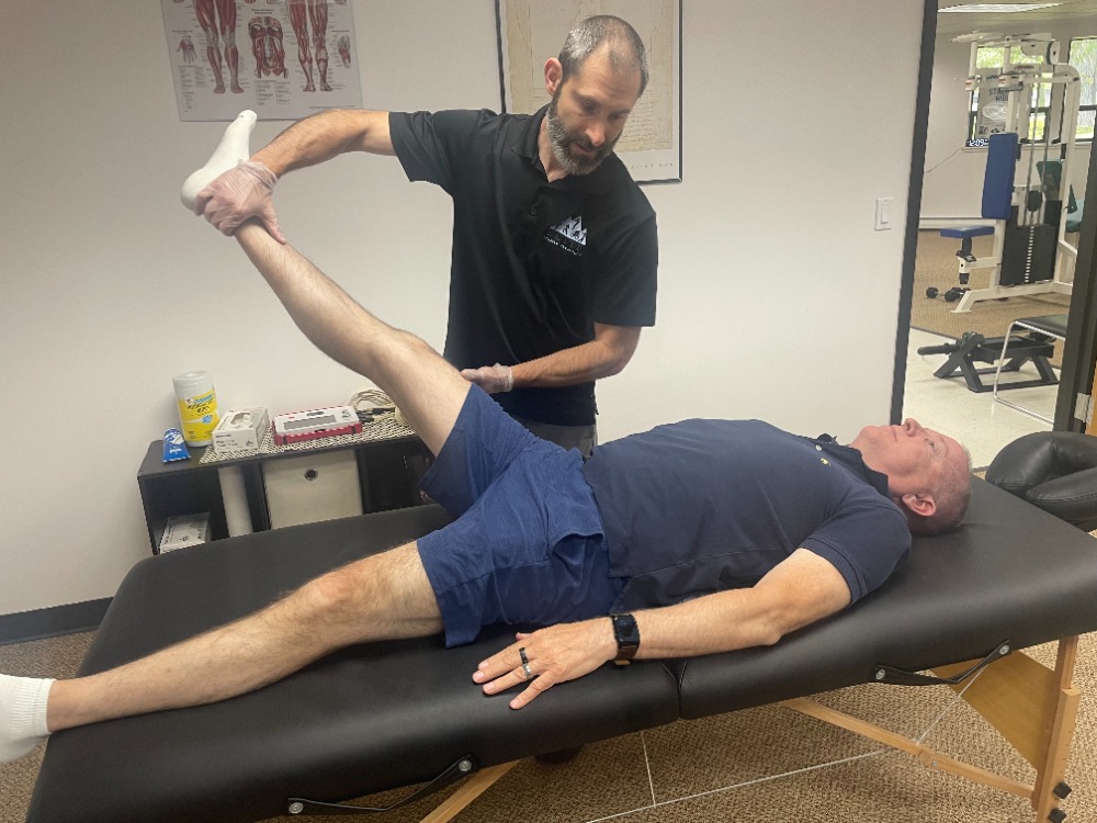 Josh assessing a client's hip range of motion during a MAT session